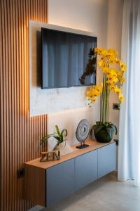 een tv aan de muur met gele bloemen op een kast bij Zen Apartments By The Sea in Kos-stad