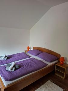 two beds in a bedroom with purple sheets at House Mara in Korenica