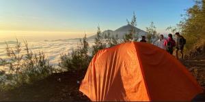 a group of people standing around an orange tent at mount batur 2 day sunset and sunsrise in Kintamani