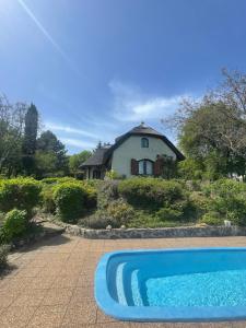 a blue swimming pool in front of a house at Szaletli in Tihany