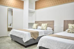 two beds in a hotel room with white walls at Santo Rio in Santa Marta +4 photos