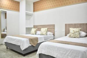 two beds in a bedroom with white walls at Santo Rio in Santa Marta