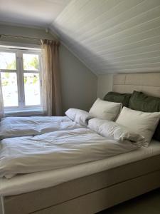 a large bed with white sheets and a window at Grandma`s house in Flåm