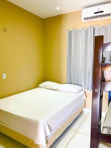 a bed in a room with a yellow wall at Ap Harmonia Bg in Barra Grande