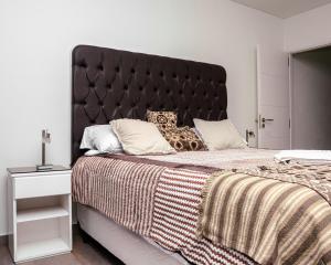 Un dormitorio con una cama grande con cabecero negro. en Departamento excelente vista.-, en Comodoro Rivadavia