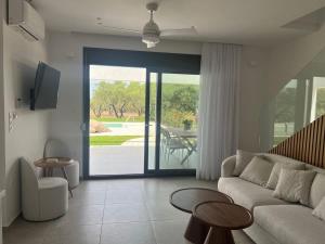 un soggiorno con un divano e una porta scorrevole in vetro di Elia Luxury Villas by Eliamare a Nea Potidaea