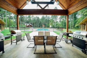een afgeschermde patio met een grill, tafels en stoelen bij Big Timber Lodge in Broken Bow
