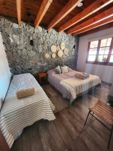 sypialnia z 2 łóżkami i kamienną ścianą w obiekcie Alquileres Cafayate w mieście Cafayate
