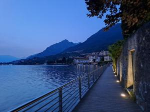 a wooden walkway next to a lake at night at Casa Romeo lago di Como in Abbadia Lariana