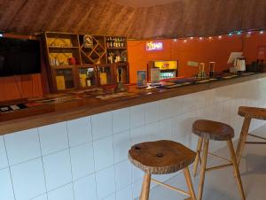 a bar with two wooden stools and a counter at Eden Villas in Entebbe