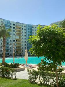 a swimming pool with an umbrella and a large building at Apartment in El Alamein,Sia Lagoon,Golf porto marina in El Alamein