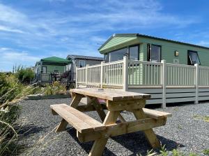 a wooden picnic table in front of a house at Cambrian Rio Caravan in Ynys-lâs Station