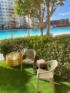 a group of chairs sitting on the grass near the water at Apartment in El Alamein,Sia Lagoon,Golf porto marina in El Alamein