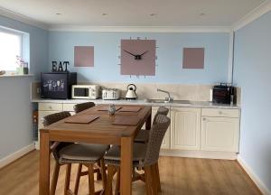 a kitchen with a wooden table and a clock on the wall at Bennett's End in Selsey