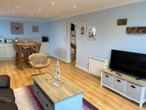 a living room with a couch and a television and a table at Bennett's End in Selsey