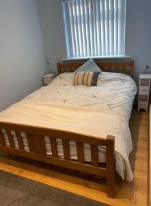a bed with a wooden frame in a bedroom at Bennett's End in Selsey +1 photo