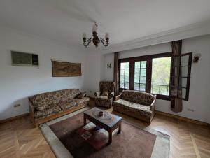 a living room with couches and a table and windows at Villa Maadi 35 -R 103- Garden & Pool Master Room in Cairo