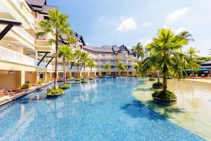 a swimming pool with palm trees in front of a building at Angsana Laguna Phuket in Bang Tao Beach