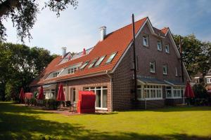 a large brick house with red chairs on the lawn at Suitenhotel Idyll Heckenrose in Langeoog