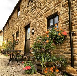 a brick building with flowers in front of it at Riding house Farm Cottages in Castleton