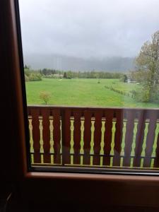 a view of a green field from a window at House Mara in Korenica