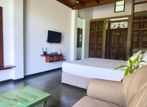 a bedroom with a bed and a tv and a couch at Green Hideaway - Villa with Private Pool, 8 mins to Galle Fort in Galle