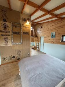 um quarto com uma cama em uma sala com paredes de madeira em Cabañas Rewe del Maulllin em Puerto Varas