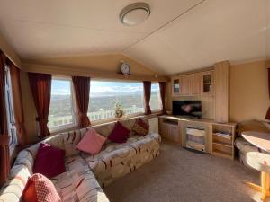 a living room with a couch and a television at Cambrian Rio Caravan in Ynys-lâs Station