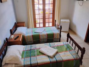 two twin beds in a room with a window at pousada Boa vista in Santo Antônio do Pinhal