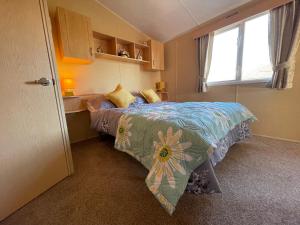 a bedroom with a bed with a colorful comforter and a window at Cambrian Rio Caravan in Ynys-lâs Station +52 photos