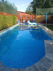 a blue swimming pool with a slide in a yard at La Plantă-Therme Airport Bucharest in Baloteşti