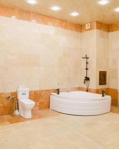 a bathroom with a bath tub and a toilet at Olive Garden Baku Hotel in Baku