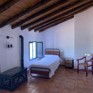 een slaapkamer met een bed en een stoel bij Cortijo Bachiller Alora 18 personas Fiestas tranquilas in Alora