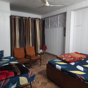 a living room with two beds and a chair at Kaushik Cottage Home Stay Mussorie in Mussoorie