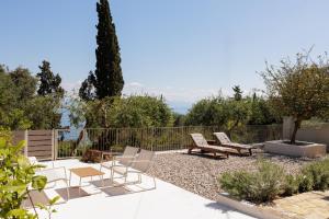 a patio with chairs and tables and a fence at OPSTANTE Corfu in Benitses