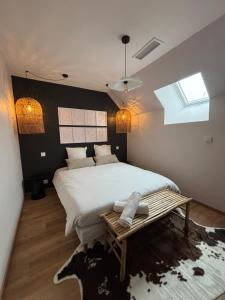 Un dormitorio con una cama grande y una mesa. en La Longère - Gîte 4 étoiles, en Alleyrat