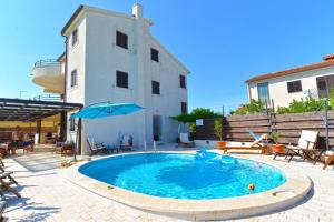 a swimming pool with an umbrella next to a building at Charming flat with shared pool in Peroj