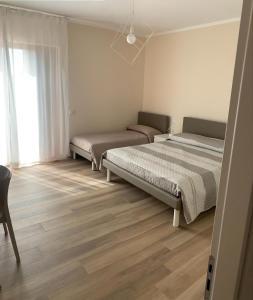 2 łóżka w sypialni z drewnianą podłogą w obiekcie La Casa de Anto' w mieście Torre San Patrizio