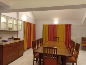 a dining room with a table and chairs and curtains at Aanandi Bunglow 3Bhk in Parhūr +3 photos