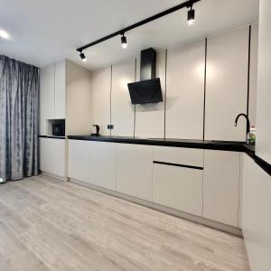 una cucina con armadi bianchi e una TV a parete di ApartPoltava Graphite Luxe Ремонт 2025 Престижна новобудова в ЦЕНТРІ міста a Poltava Altre 10 foto