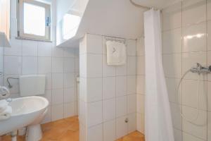 a white bathroom with a sink and a shower at Villa Dorijana, a beachfront holiday home in Plomin +22 photos