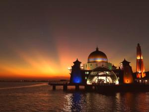 a building with a dome on the water at night at Ringo's Foyer in Melaka