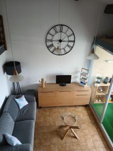 a living room with a couch and a clock on the wall at Appartement 2 chambres dans la marina in Saint-Cyprien-Plage +4 photos