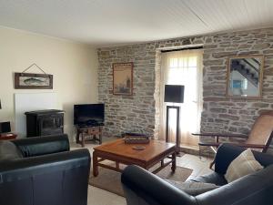 a living room with furniture and a stone wall at Adorable Penty en pierres en bord de mer in Tréogat