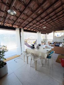 Un comedor con mesa y sillas y el océano. en Casa na Ilha Jardim pé na areia, en Río de Janeiro