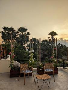 a patio with chairs and tables and palm trees at Villa with Private Pool, 12 mins walk to Beach in Trincomalee