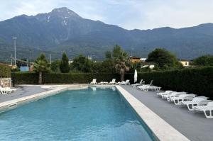 a swimming pool with lounge chairs and a mountain at Residence Lario Village in Colico