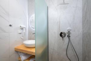 a shower in a bathroom with a sink at Opalium Beach Front Suites in Potos