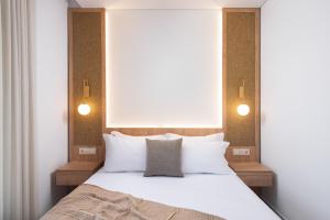 a bedroom with a white bed with two lights on it at Opalium Beach Front Suites in Potos +37 photos