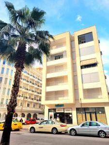 a palm tree and cars parked in front of a building at Appartament ZEA in Durrës